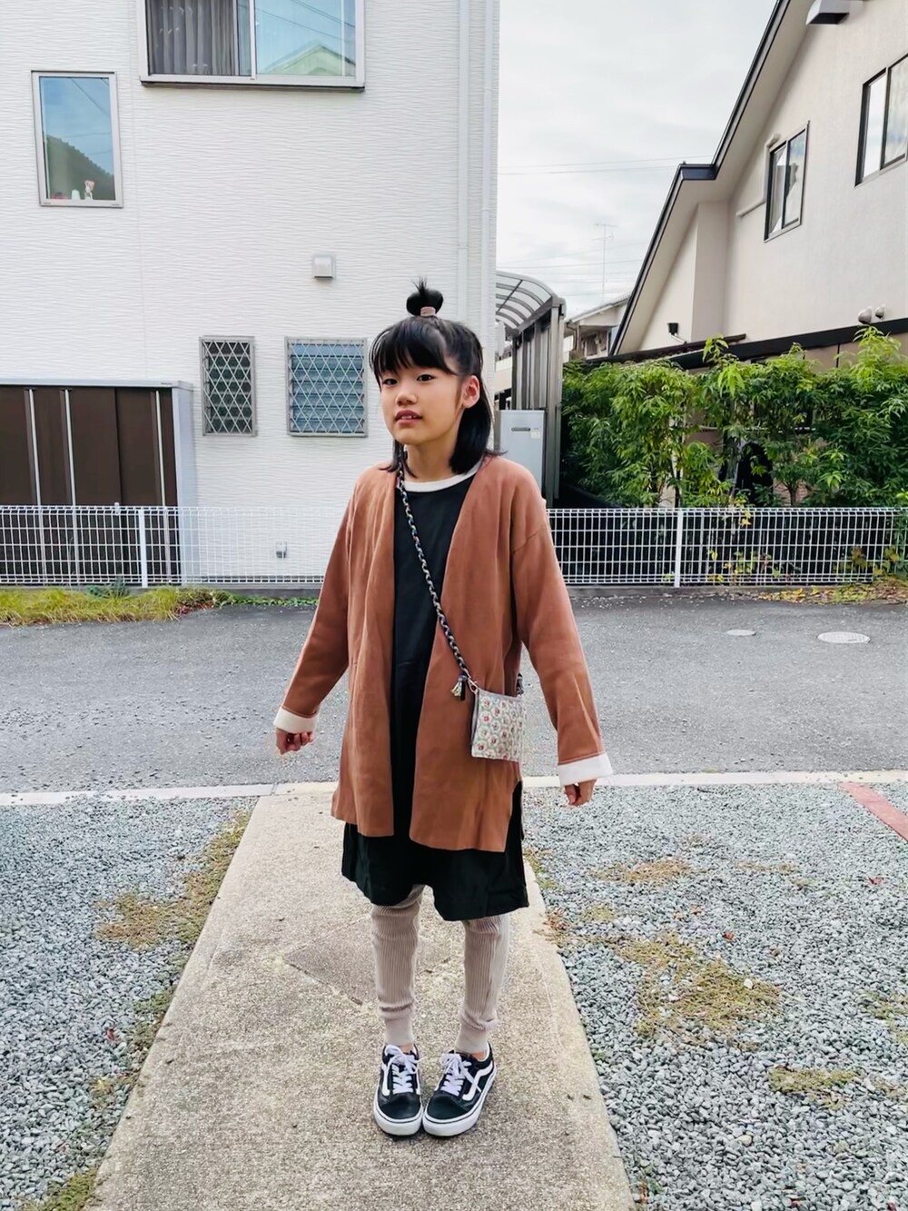 ブラウン系のカーディガン/ボレロ、ブラック系のスニーカー、ホワイト系のワンピースを着用したキッズの秋コーディネートの2枚目の写真