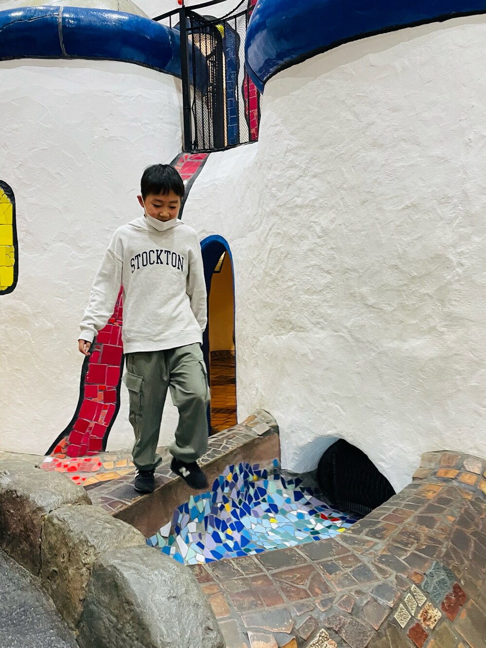 グレー系のTシャツ/カットソー、ブラック系のダウンジャケット/コート、ブラック系のスニーカーを着用したキッズの冬コーディネートの3枚目の写真