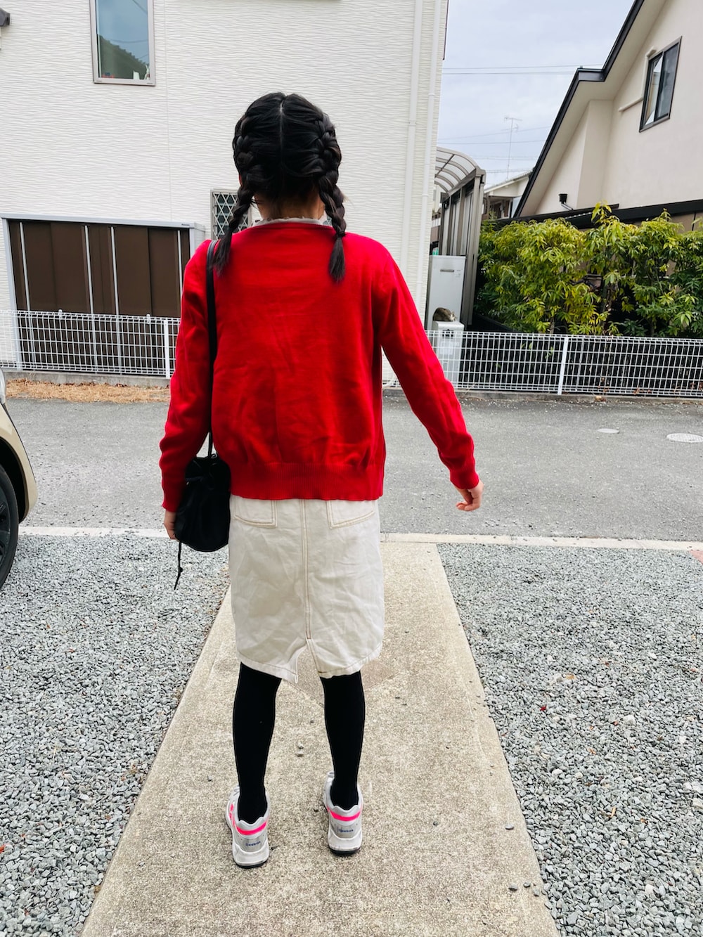 ブラック系のハンドバッグ、ホワイト系のジャンパースカート、グレー系のスニーカーを着用したキッズの冬コーディネートの3枚目の写真