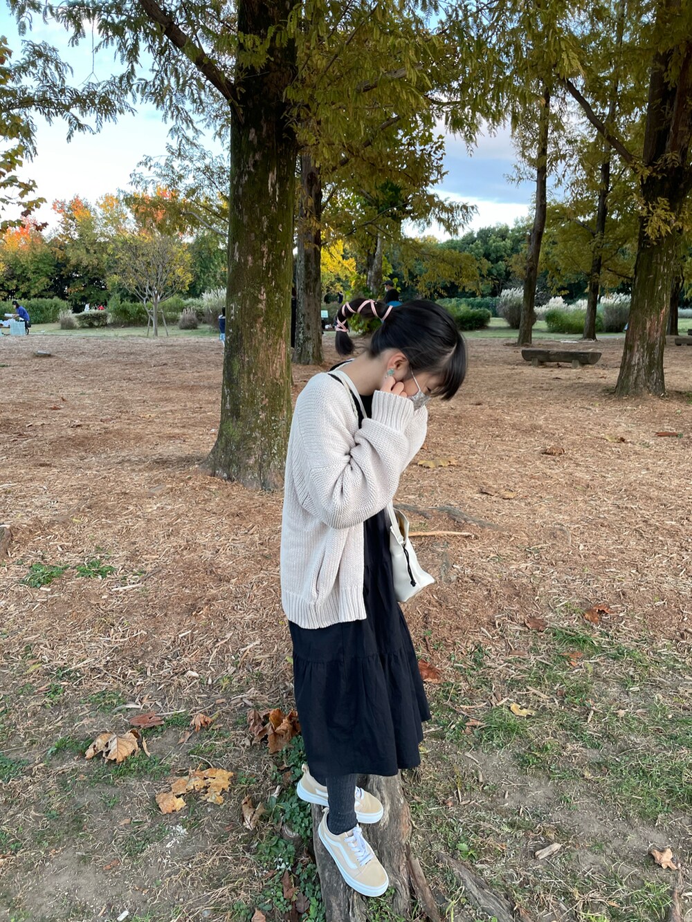 ブラック系のワンピース、ホワイト系のトップス、ベージュ系のスニーカーを着用したキッズの秋コーディネートの2枚目の写真