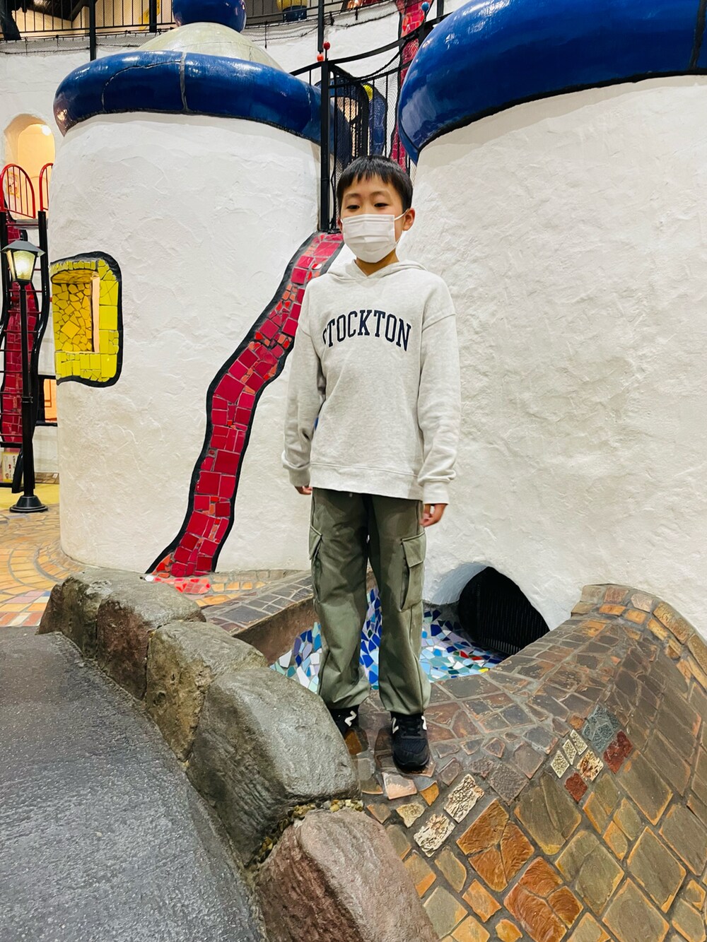 グレー系のTシャツ/カットソー、ブラック系のダウンジャケット/コート、ブラック系のスニーカーを着用したキッズの冬コーディネートの2枚目の写真