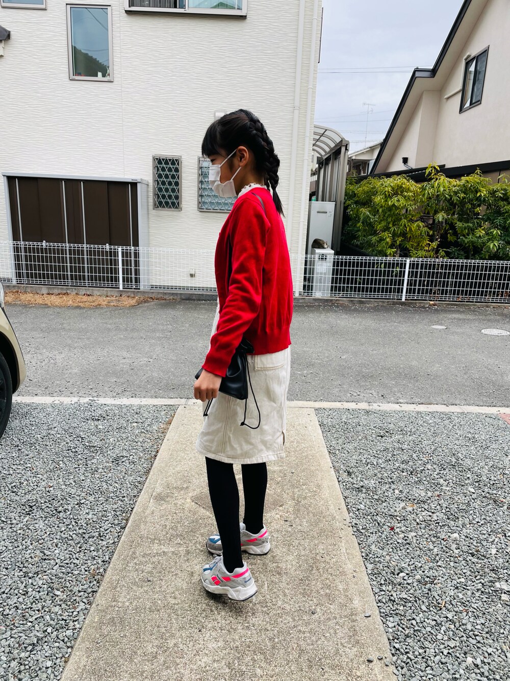 ブラック系のハンドバッグ、ホワイト系のジャンパースカート、グレー系のスニーカーを着用したキッズの冬コーディネートの2枚目の写真