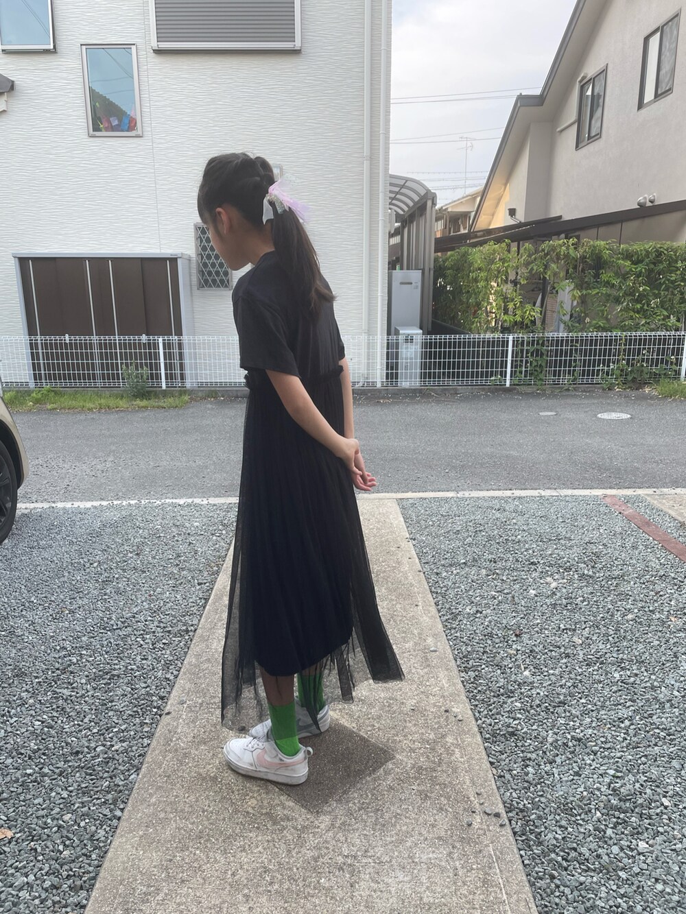 ブラック系のワンピース、ホワイト系のスニーカー、グリーン系のソックス/靴下を着用したキッズの夏コーディネートの2枚目の写真