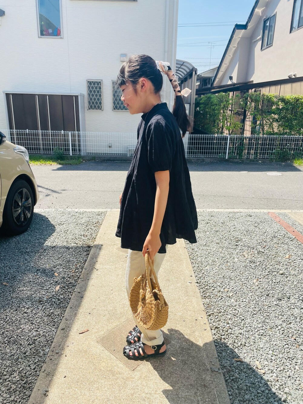 ブラック系のチュニック、ホワイト系のチノパンツ、ブラック系のサンダルを着用したキッズの夏コーディネートの2枚目の写真