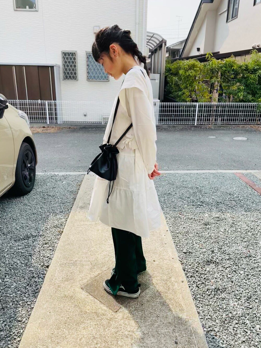 ブラック系のハンドバッグ、グリーン系のその他パンツ、ブラック系のスニーカーを着用したキッズの春コーディネートの2枚目の写真