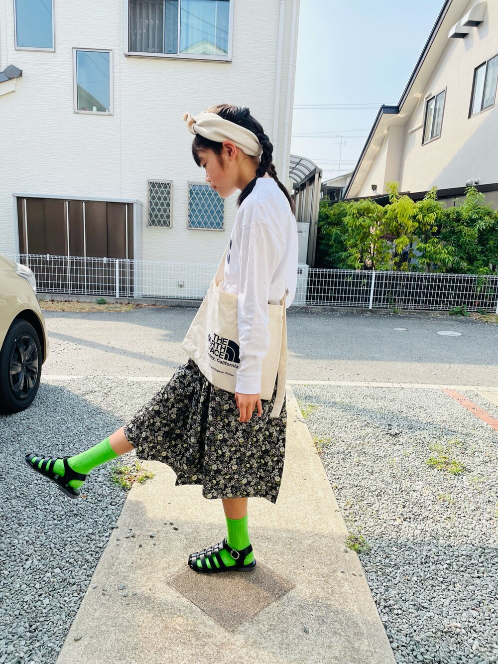 ブラック系のスカート、ブラック系のサンダル、ホワイト系のTシャツ/カットソーを着用したキッズの春コーディネートの2枚目の写真