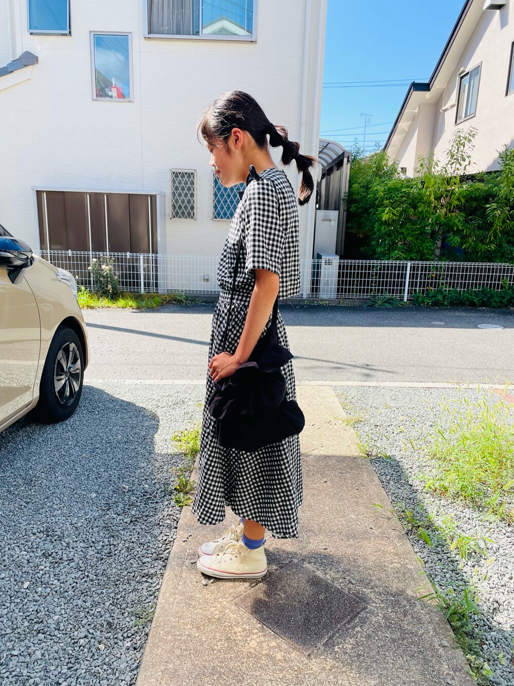 ブラック系のバッグ、ブラック系のワンピース、ホワイト系のスニーカーを着用したキッズの夏コーディネートの2枚目の写真
