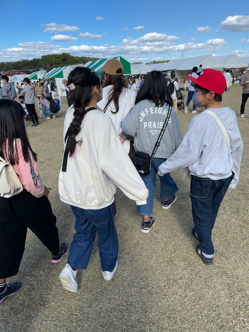 ブルー系のデニムパンツ、ホワイト系のスニーカー、ベージュ系のスウェットを着用したキッズの秋コーディネートの3枚目の写真