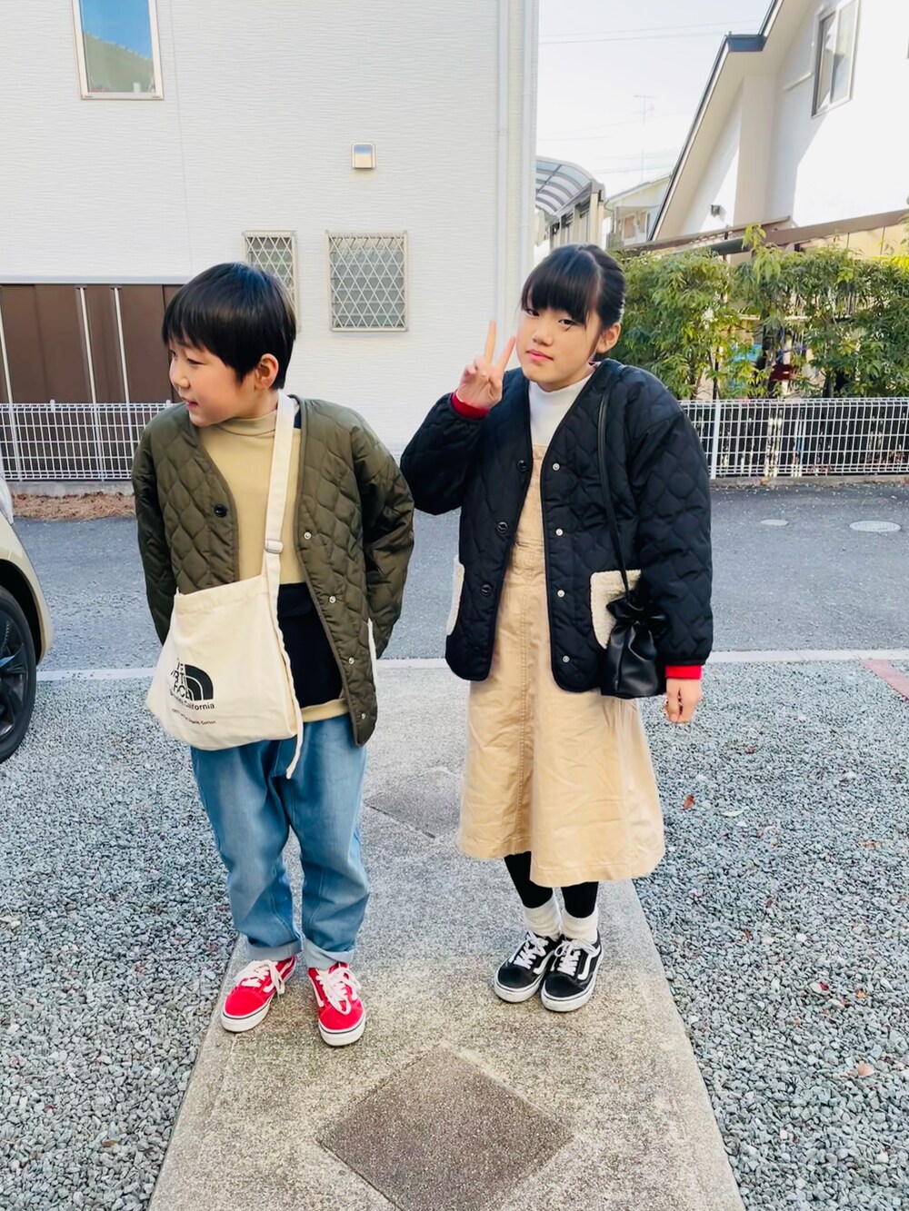 ブラック系のブルゾン、ベージュ系のジャンパースカート、ブラック系のスニーカーを着用したキッズの冬コーディネートの2枚目の写真