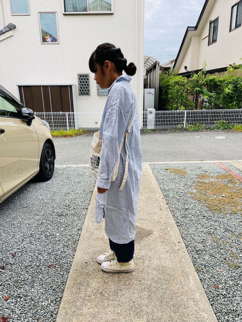 ブラック系のショルダーバッグ、ブルー系のシャツワンピース、ブルー系のデニムパンツを着用したキッズの秋コーディネートの2枚目の写真