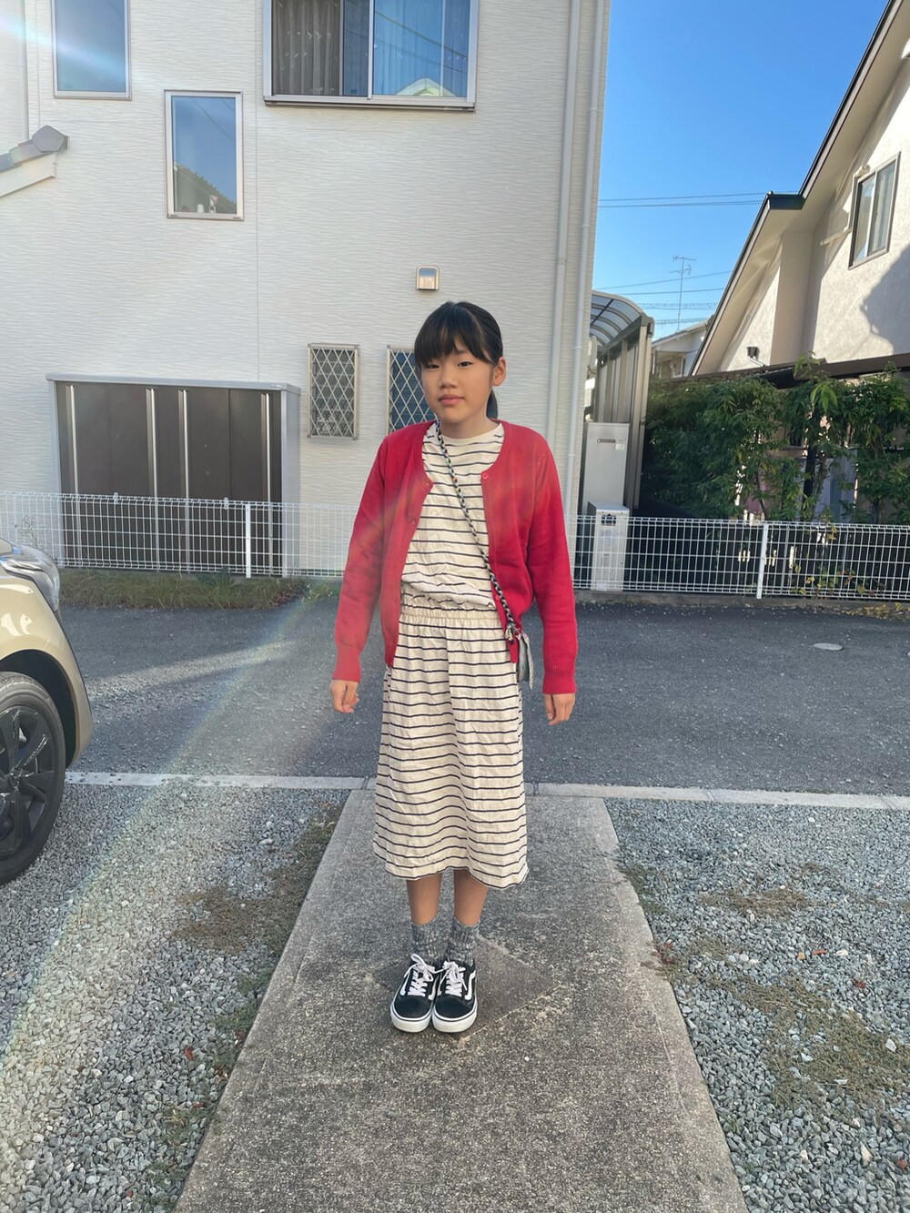 ブラック系のスニーカー、レッド系のカーディガン/ボレロ、ホワイト系のワンピースを着用したキッズの秋コーディネートの2枚目の写真