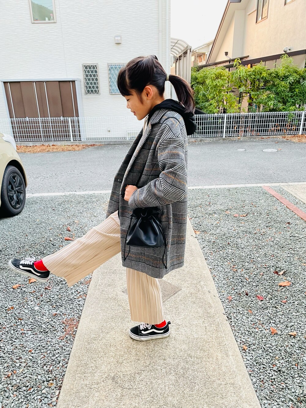 グレー系のチェスターコート、ブラック系のハンドバッグ、ブラック系のパーカーを着用したキッズの冬コーディネートの2枚目の写真