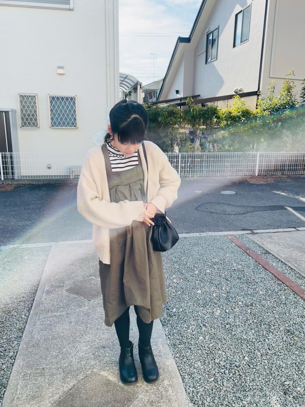 ホワイト系のカーディガン/ボレロ、グリーン系のジャンパースカート、ブラック系のブーツを着用したキッズの冬コーディネートの3枚目の写真