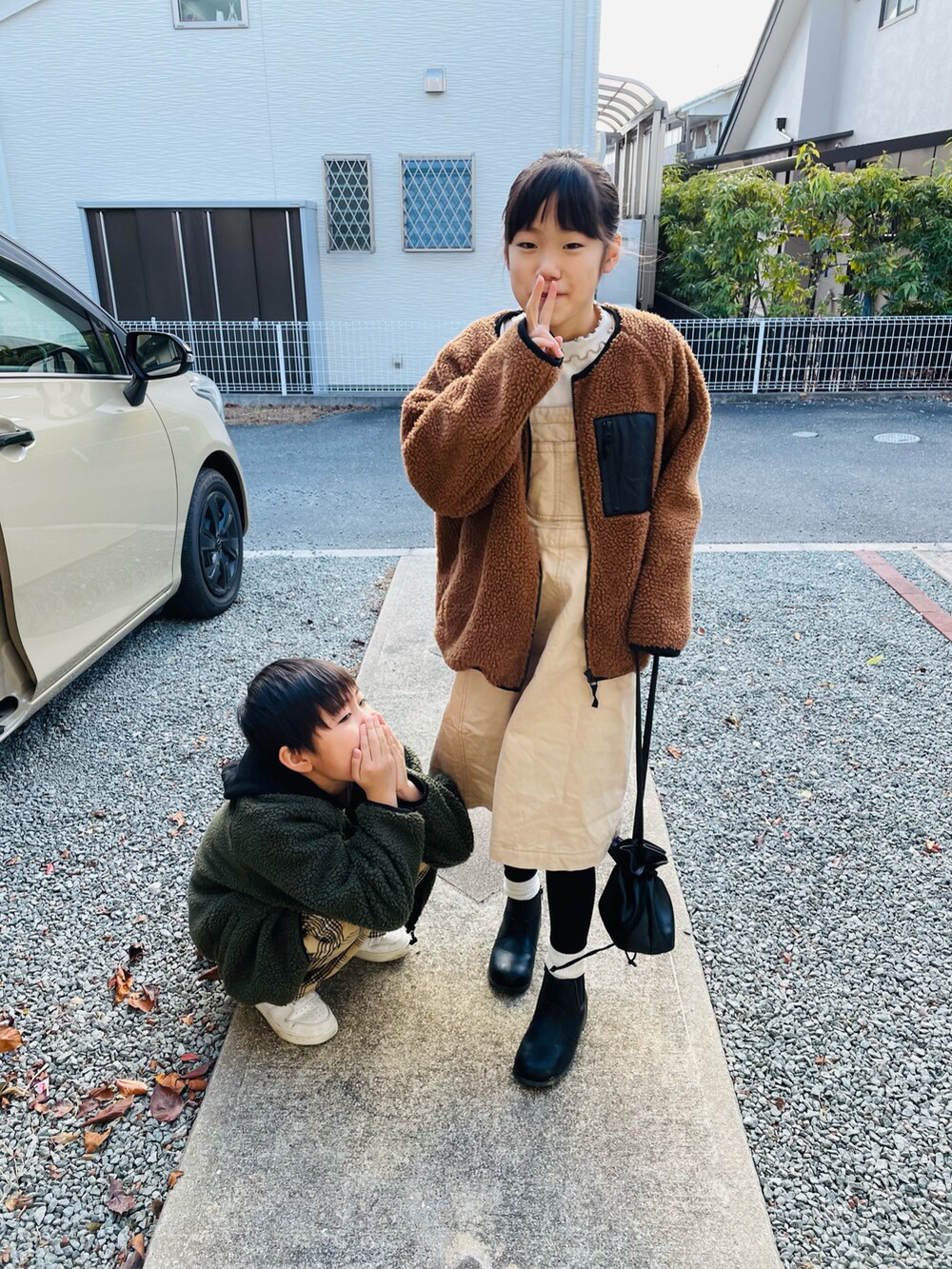 ブラウン系のその他アウター、ベージュ系のジャンパースカート、ブラック系のブーツを着用したキッズの冬コーディネートの3枚目の写真