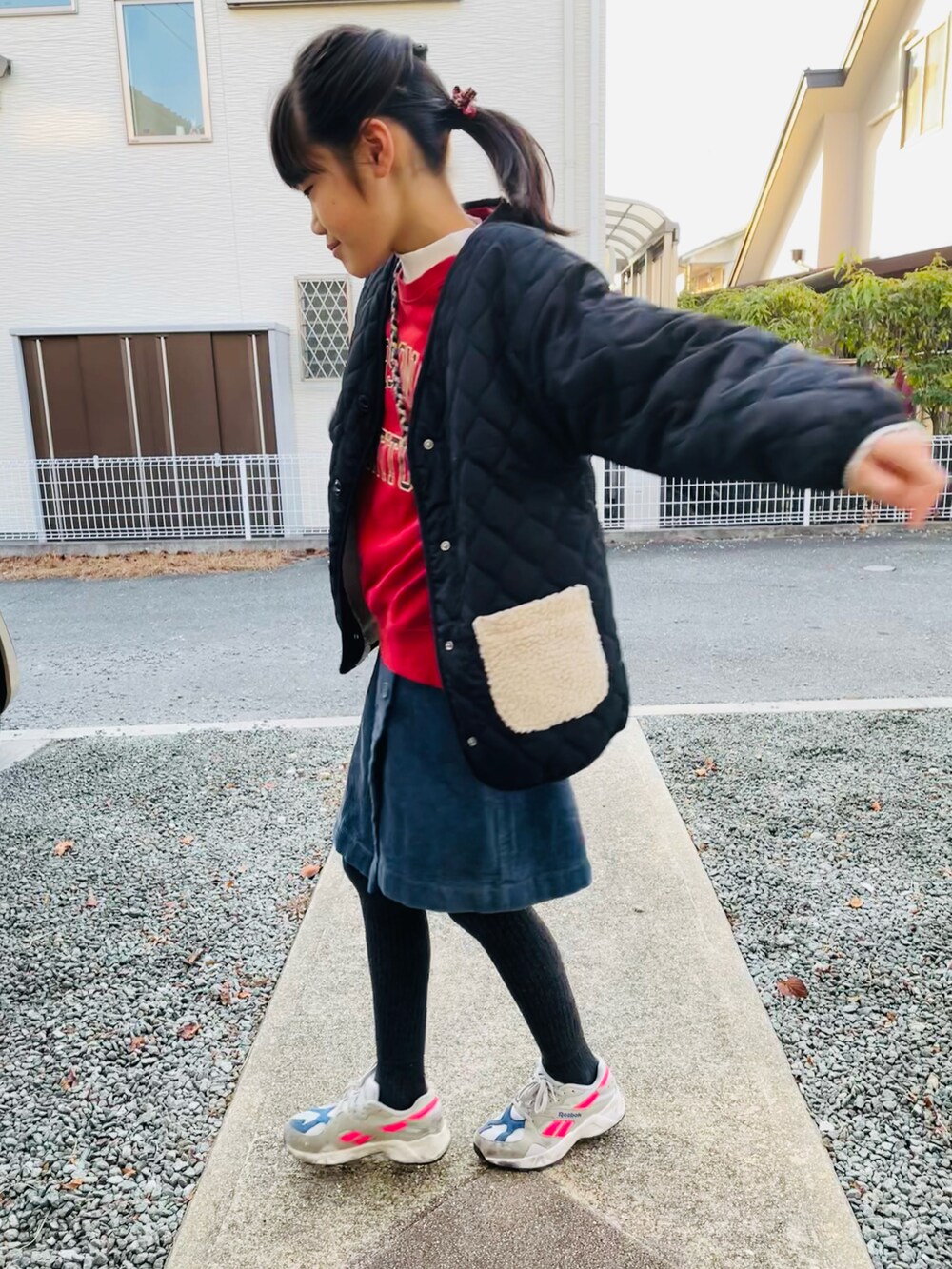 レッド系のスウェット、ブラック系のブルゾン、ブルー系のスカートを着用したキッズの冬コーディネートの2枚目の写真