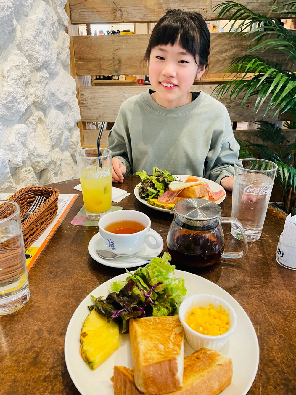 グリーン系のワンピース、ホワイト系のスニーカー、ブラック系のキャップを着用したキッズの春コーディネートの3枚目の写真