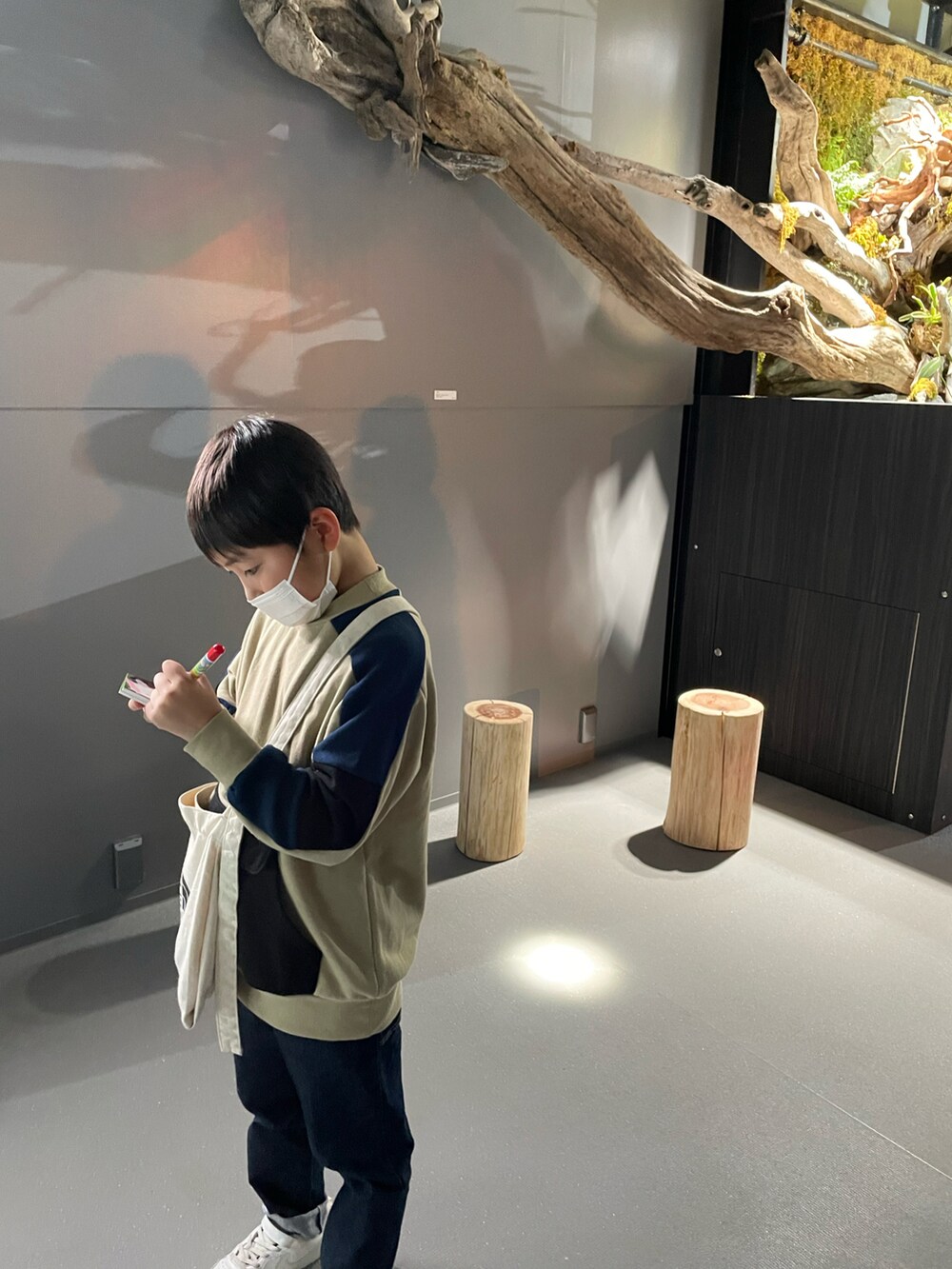 ホワイト系のスニーカー、ブルー系のデニムパンツ、ブラック系のショルダーバッグを着用したキッズの冬コーディネートの3枚目の写真