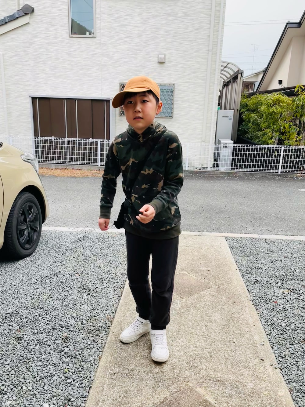 グリーン系のパーカー、ホワイト系のスニーカー、オレンジ系のキャップを着用したキッズの冬コーディネートの3枚目の写真