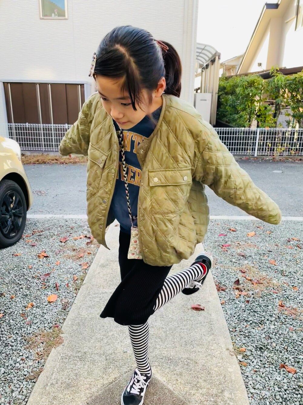 グリーン系のブルゾン、ブラック系のスカート、ブルー系のスウェットを着用したキッズの秋コーディネートの2枚目の写真