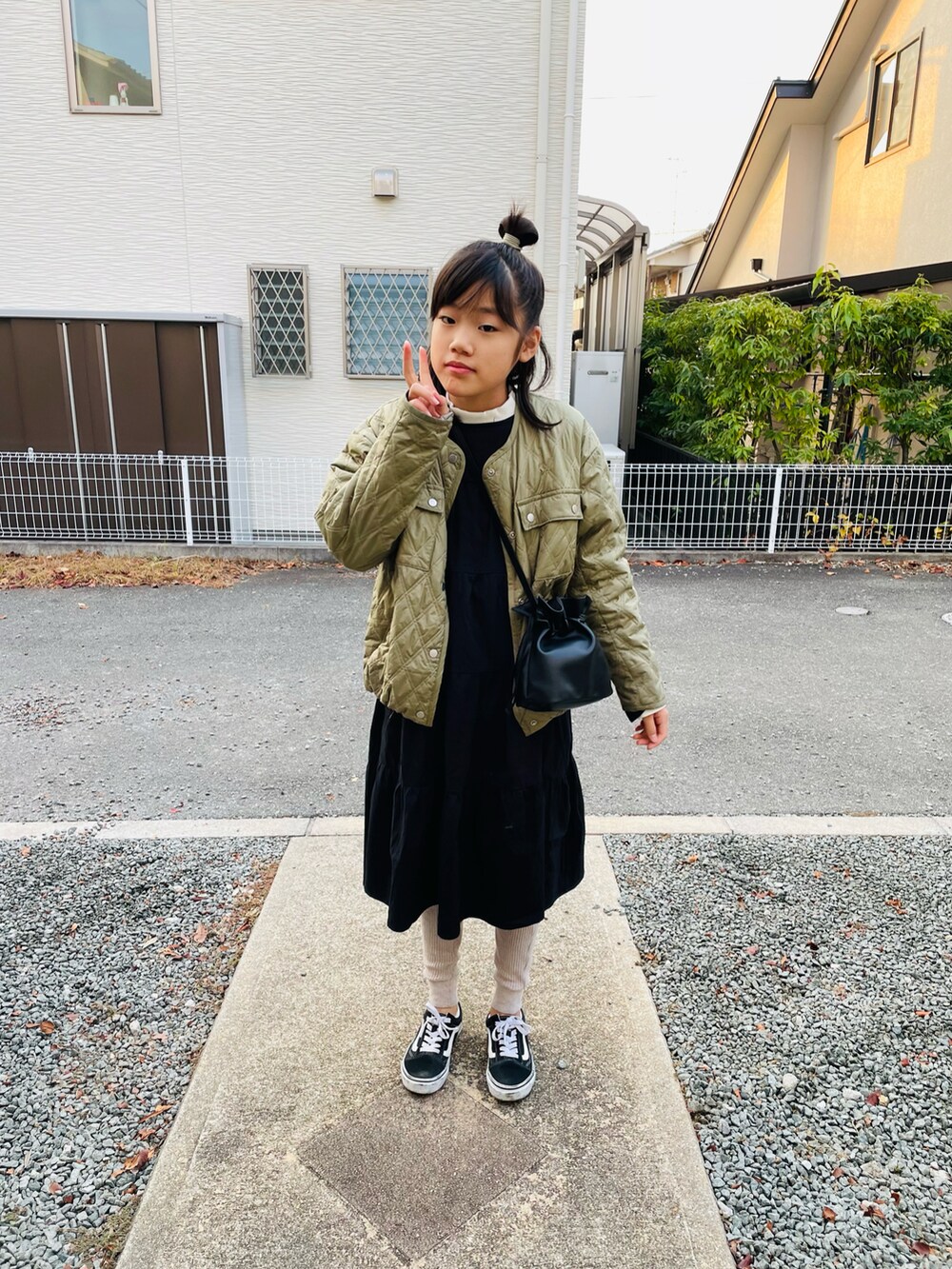 グリーン系のブルゾン、ブラック系のワンピース、ホワイト系のTシャツ/カットソーを着用したキッズの冬コーディネートの2枚目の写真