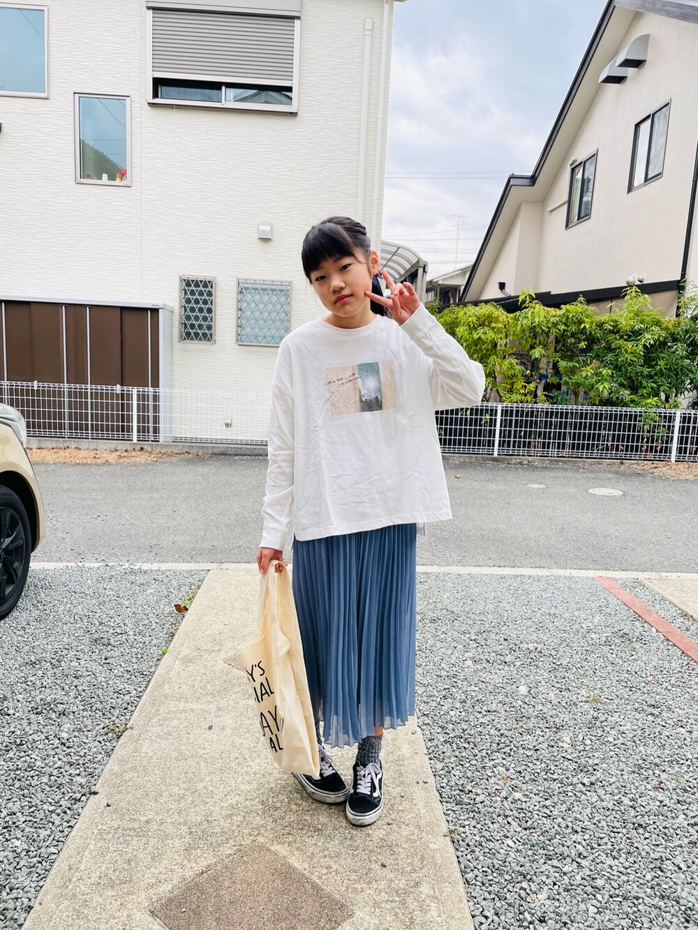 ホワイト系のTシャツ/カットソー、ブルー系のスカート、ホワイト系のエコバッグ/サブバッグを着用したキッズの春コーディネートの2枚目の写真