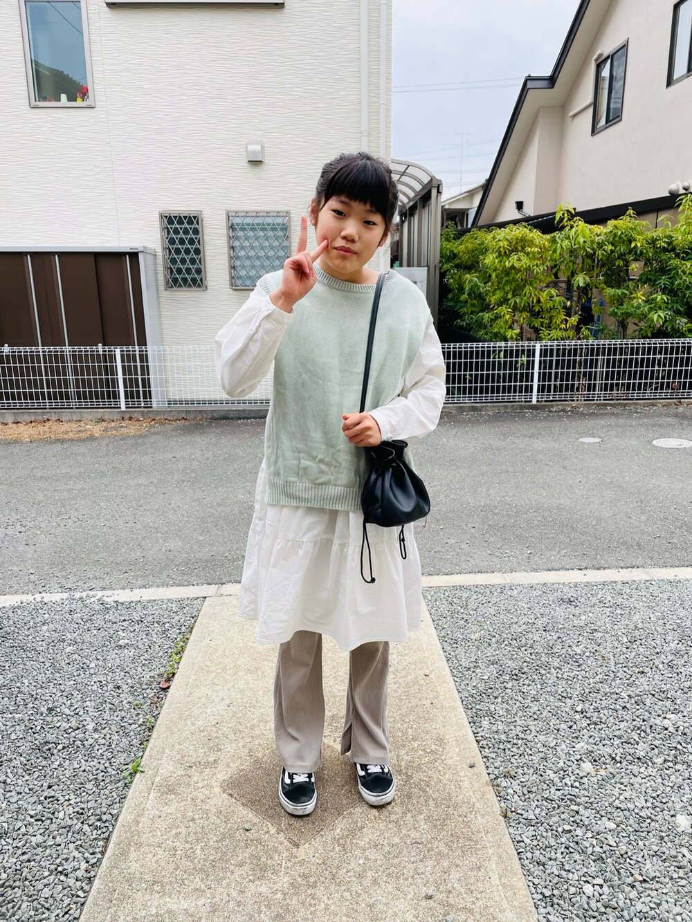 ブラック系のハンドバッグ、グリーン系のワンピース、ホワイト系のワンピースを着用したキッズの春コーディネートの2枚目の写真