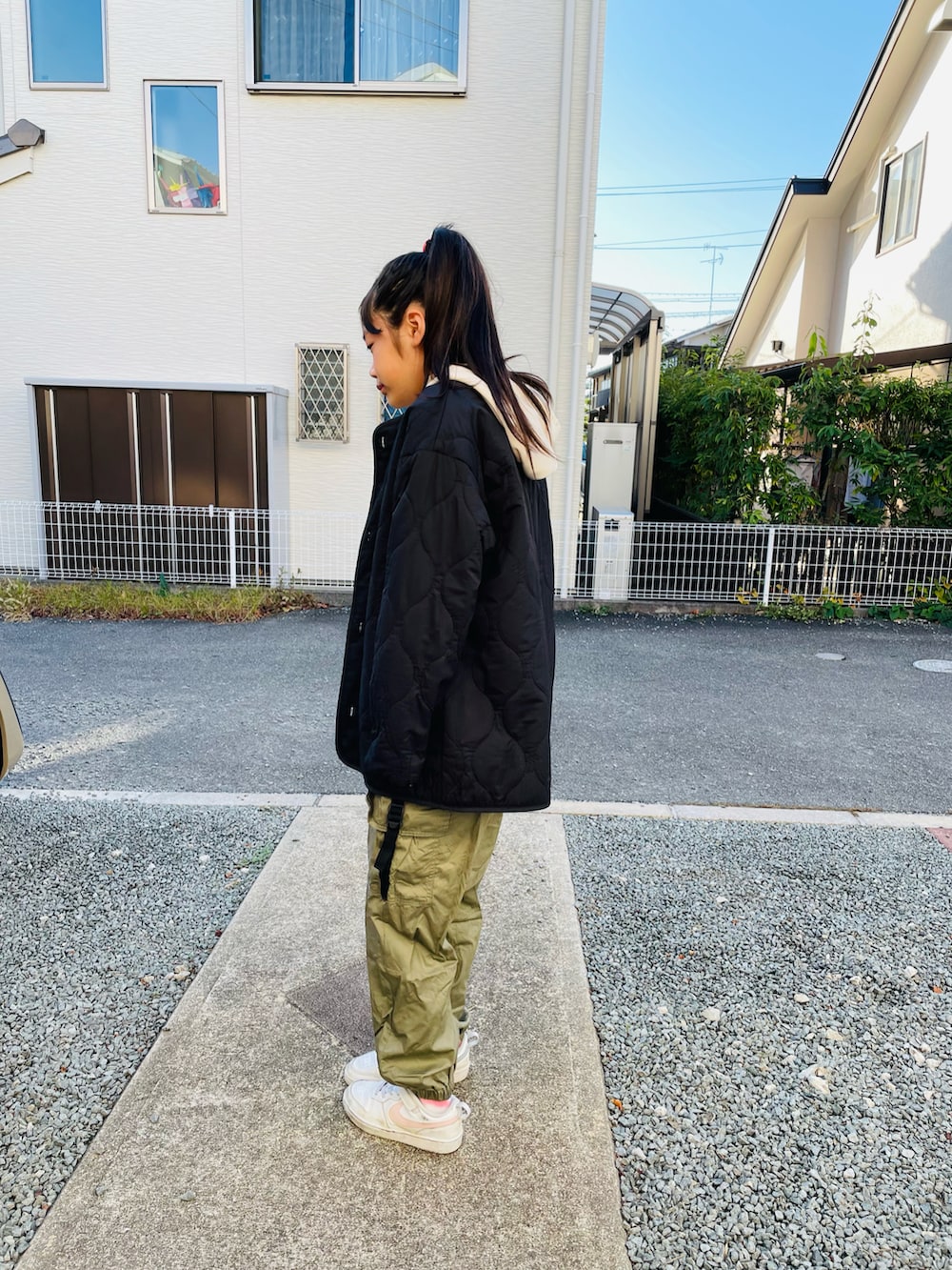 ブラック系のモッズコート、ホワイト系のスニーカーを着用したキッズの秋コーディネートの2枚目の写真