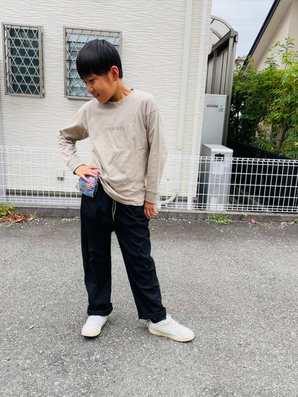 ブラック系のその他パンツ、ホワイト系のスニーカー、ベージュ系のTシャツ/カットソーを着用したキッズの秋コーディネートの3枚目の写真