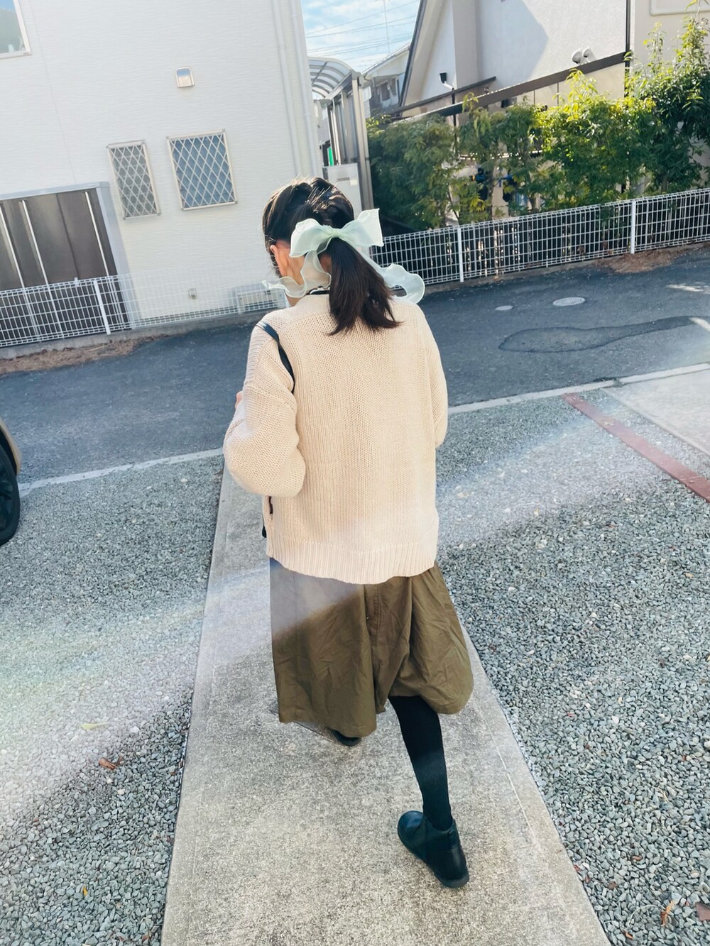 ホワイト系のカーディガン/ボレロ、グリーン系のジャンパースカート、ブラック系のブーツを着用したキッズの冬コーディネートの5枚目の写真