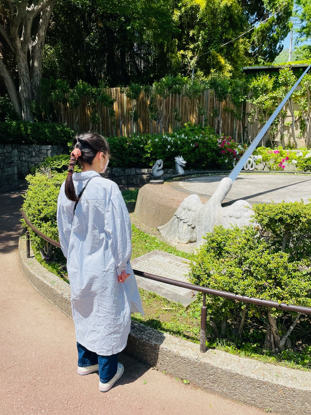 ブルー系のシャツワンピース、ブラック系のハンドバッグ、ブルー系のデニムパンツを着用したキッズの春コーディネートの4枚目の写真