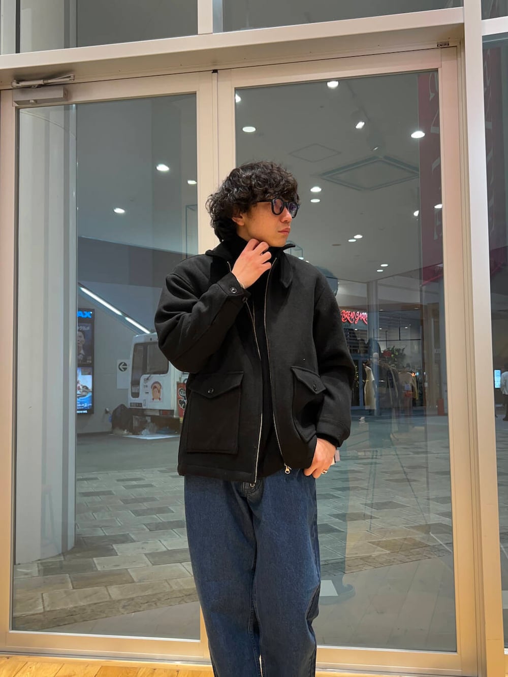 ブルー系のデニムパンツ、ブラック系のニット/セーター、ブラック系のその他アウターを着用したメンズの冬コーディネートの2枚目の写真