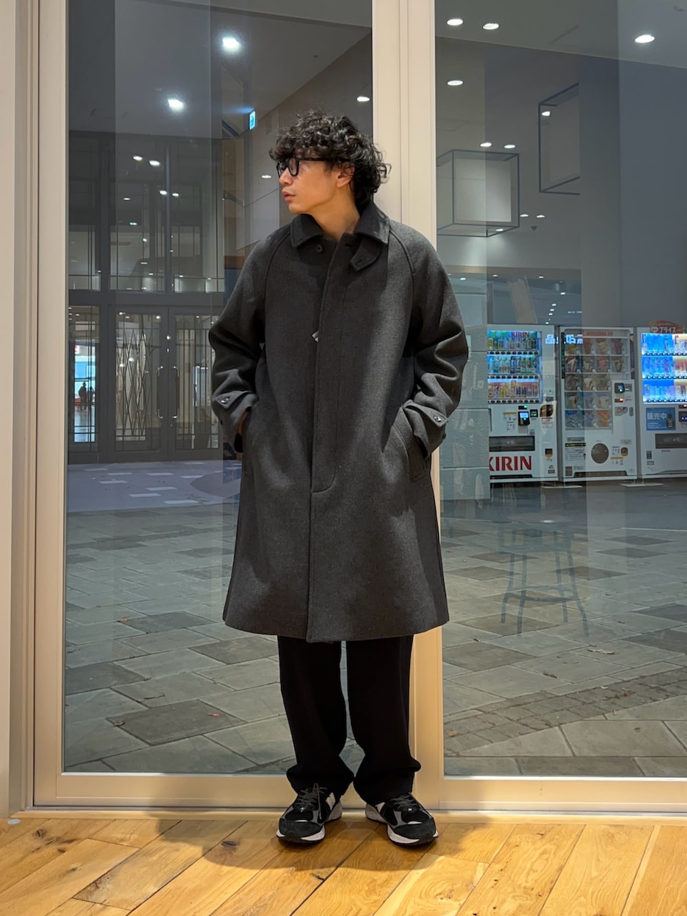 グレー系のステンカラーコート、グリーン系のニット/セーター、ブルー系のその他パンツを着用したメンズの冬コーディネートの2枚目の写真