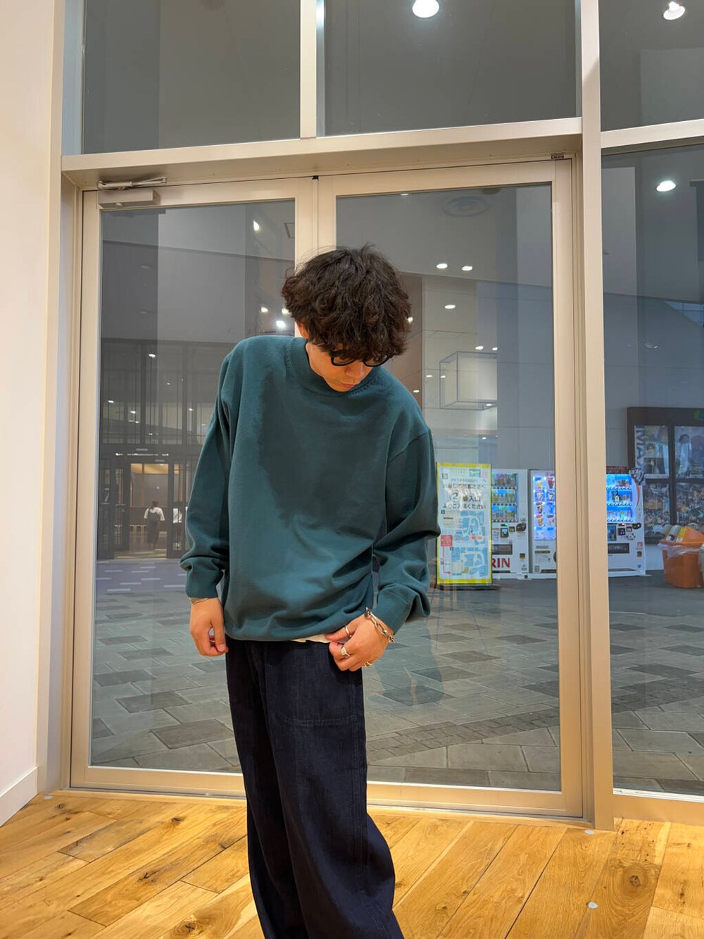 ブラック系のスニーカー、ブルー系のデニムパンツ、グリーン系のニット/セーターを着用したメンズの秋コーディネートの3枚目の写真