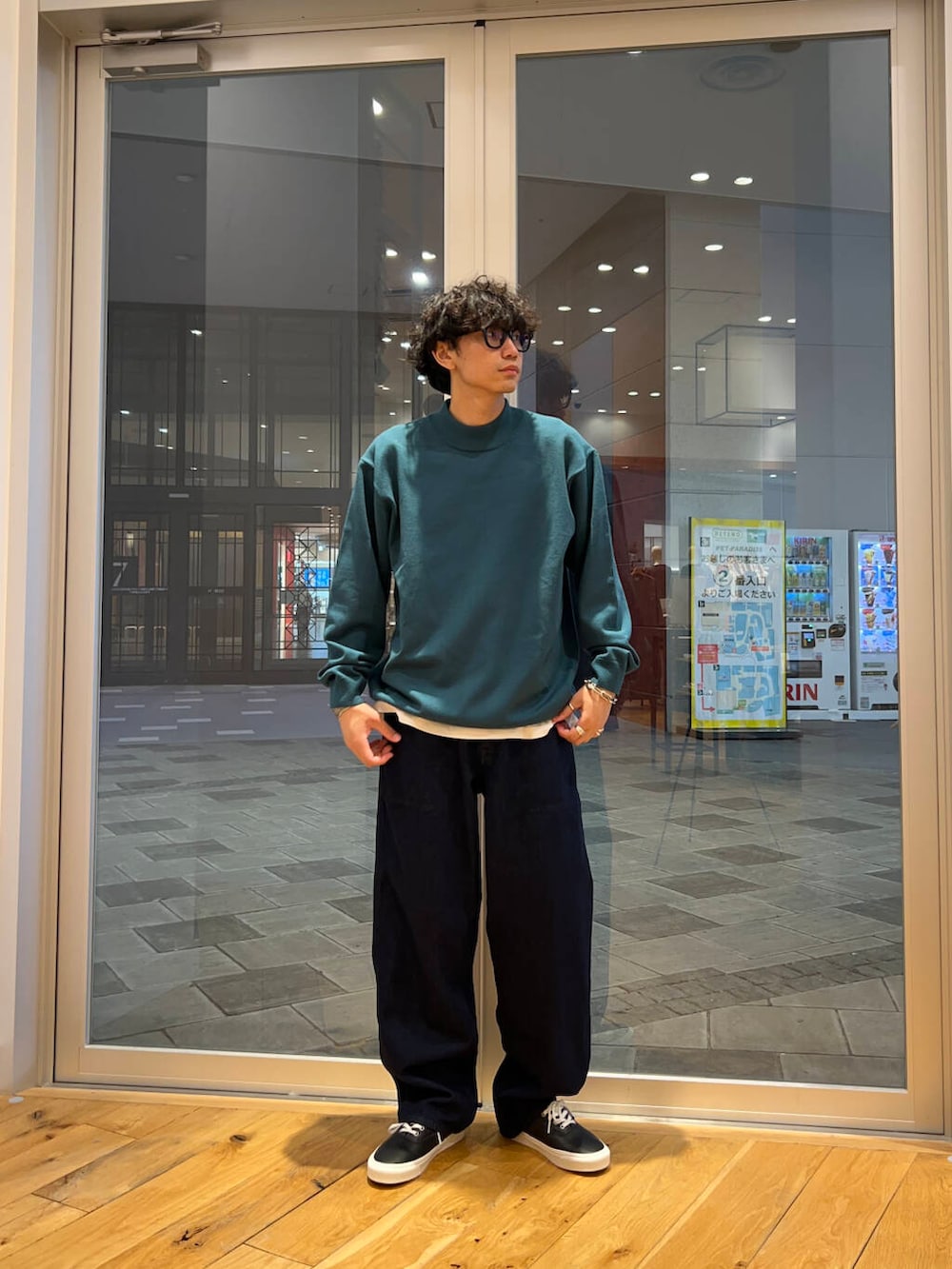 ブラック系のスニーカー、ブルー系のデニムパンツ、グリーン系のニット/セーターを着用したメンズの秋コーディネートの2枚目の写真