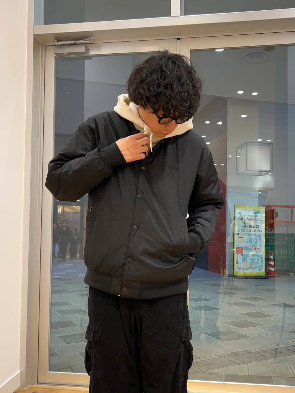 ブラック系のブーツ、ブラック系のダウンジャケット/コート、ホワイト系のパーカーを着用したメンズの秋コーディネートの3枚目の写真