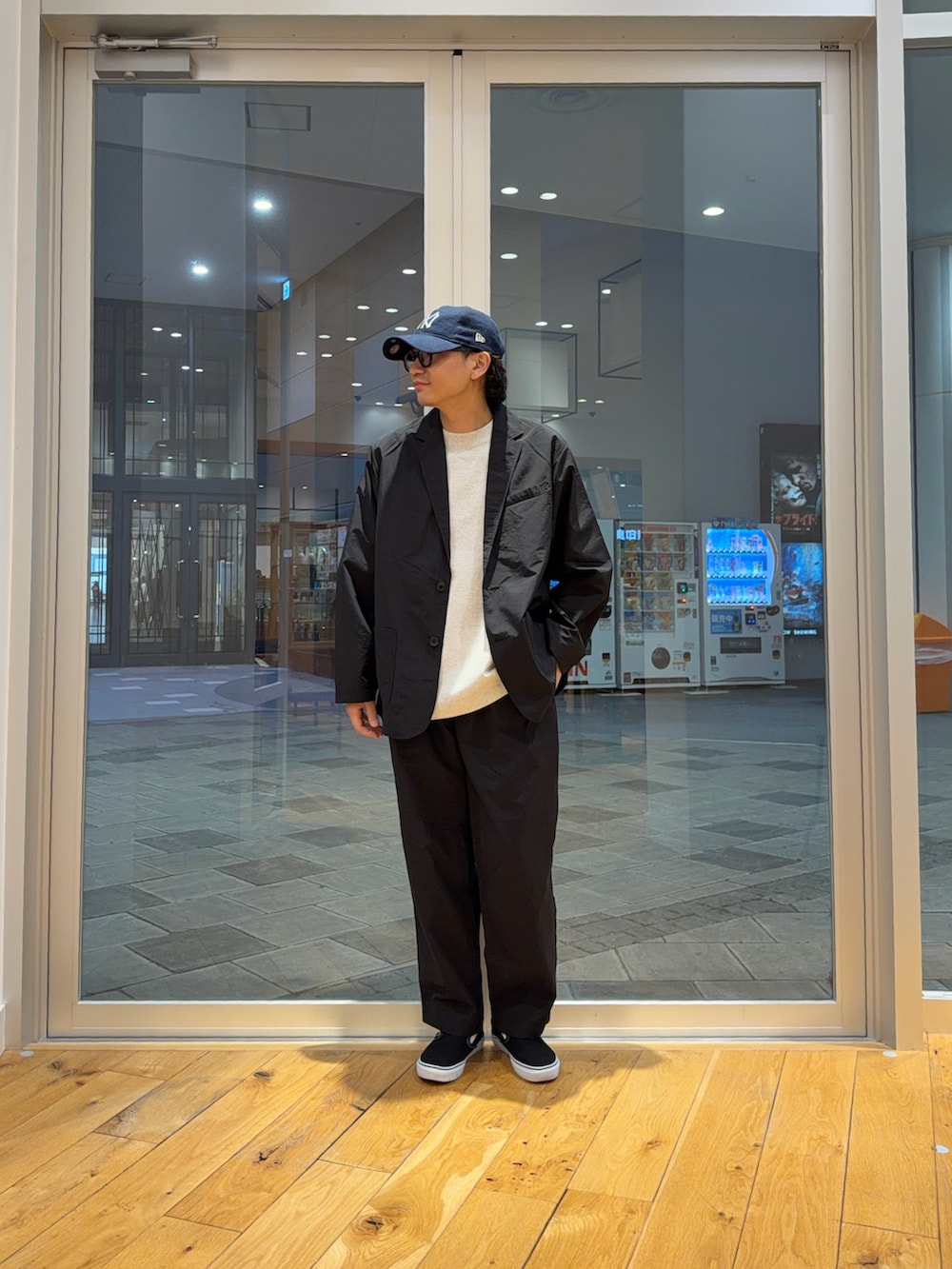 ブラック系のその他アウター、ブラック系のその他パンツ、ブルー系のキャップを着用したメンズの春コーディネートの2枚目の写真