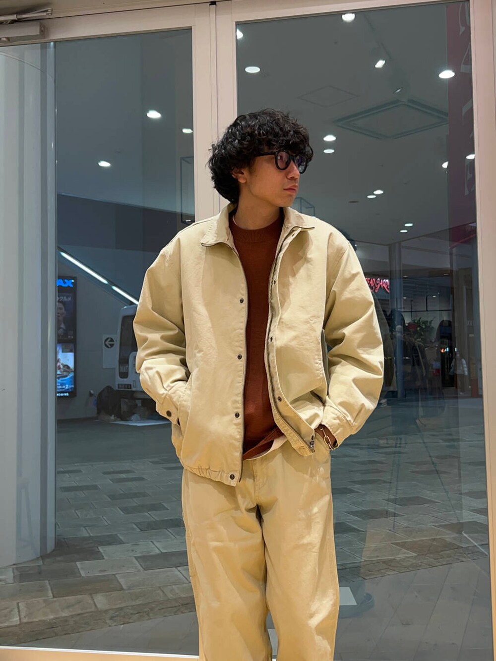 オレンジ系のニット/セーター、ベージュ系のその他パンツ、ベージュ系のダウンジャケット/コートを着用したメンズの冬コーディネートの3枚目の写真