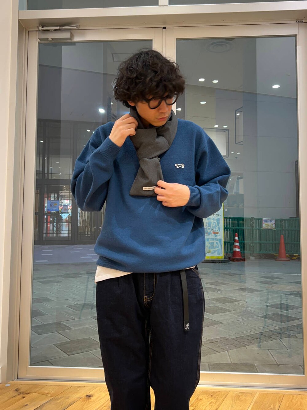 ブルー系のデニムパンツ、ブルー系のニット/セーター、グレー系のマフラーを着用したメンズの秋コーディネートの3枚目の写真