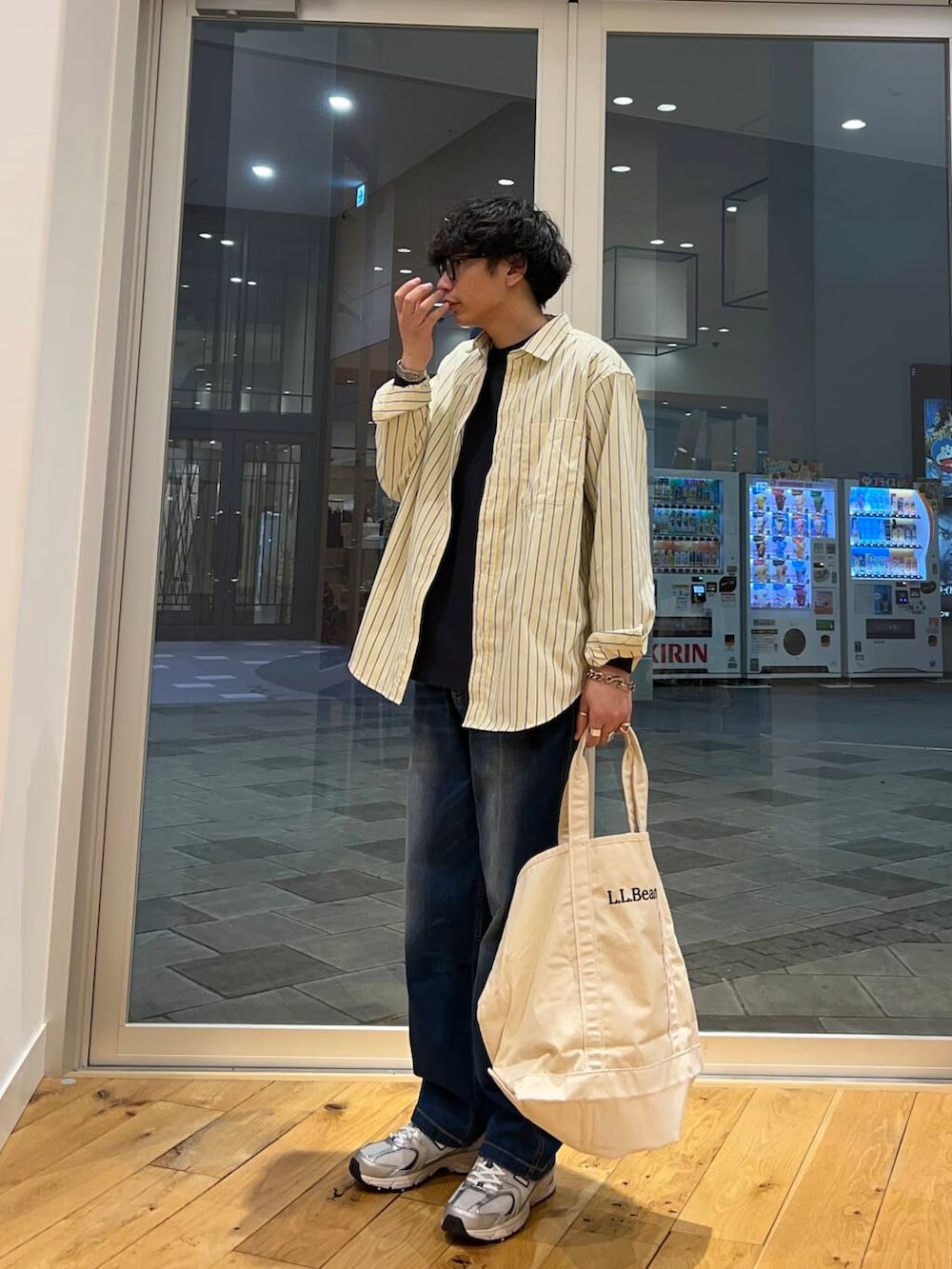 ホワイト系のトートバッグ、ブルー系のデニムパンツ、ブラック系のTシャツ/カットソーを着用したメンズの春コーディネートの3枚目の写真