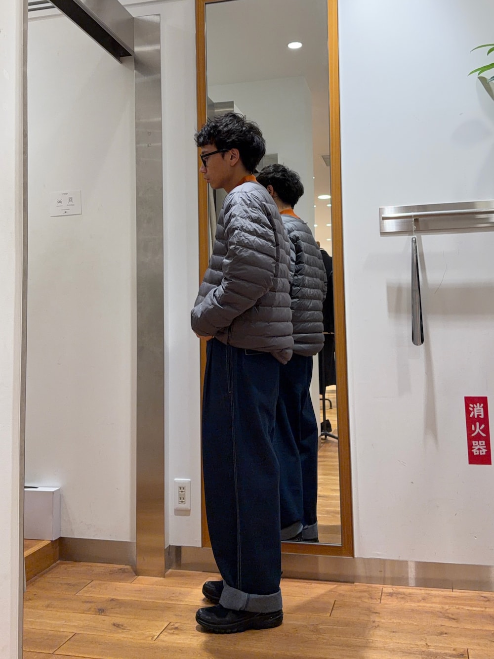 ブルー系のその他パンツ、オレンジ系のニット/セーター、ブラック系のダウンジャケット/コートを着用したメンズの秋コーディネートの3枚目の写真