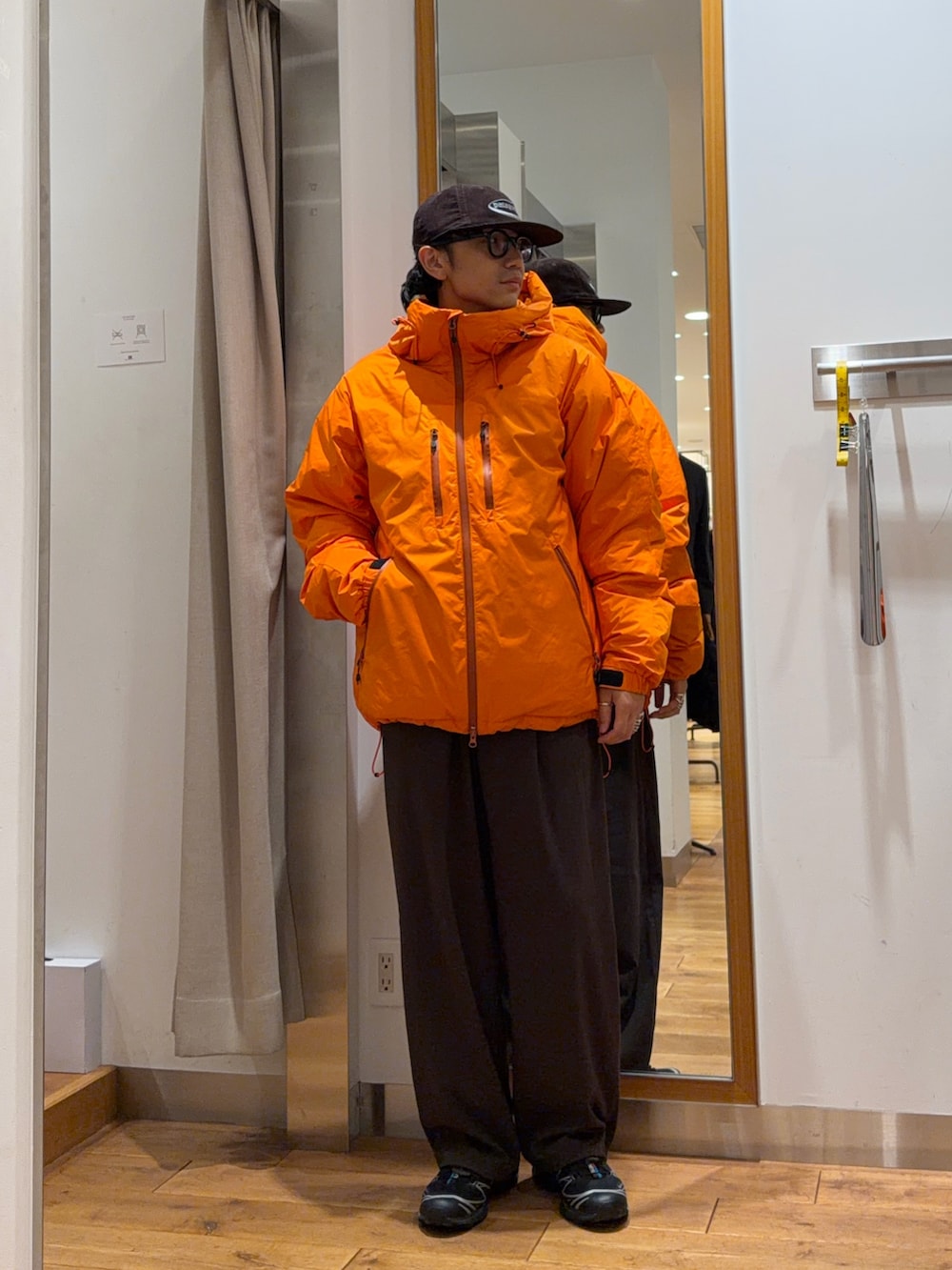 ブラウン系のその他パンツ、オレンジ系のダウンジャケット/コート、ブラウン系のキャップを着用したメンズの秋コーディネートの5枚目の写真