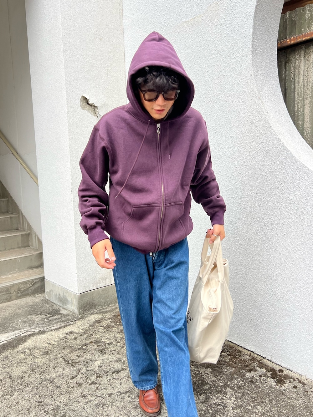 パープル系のパーカー、ブルー系のデニムパンツを着用したメンズの秋コーディネートの2枚目の写真