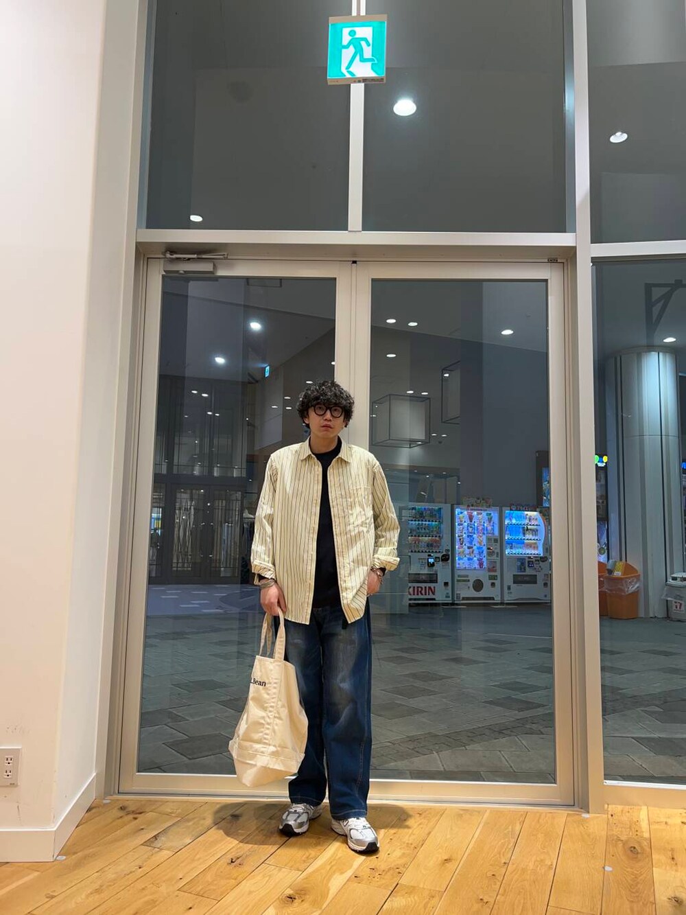 ホワイト系のトートバッグ、ブルー系のデニムパンツ、ブラック系のTシャツ/カットソーを着用したメンズの春コーディネートの2枚目の写真