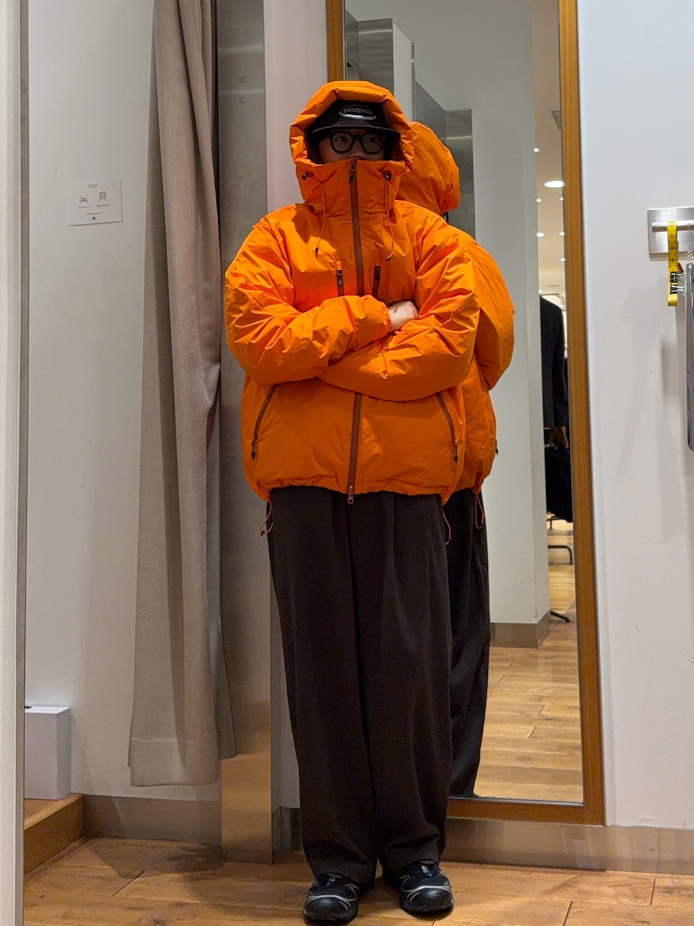ブラウン系のその他パンツ、オレンジ系のダウンジャケット/コート、ブラウン系のキャップを着用したメンズの秋コーディネートの2枚目の写真