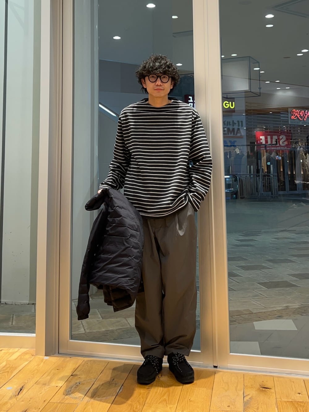 グレー系のその他パンツ、グレー系のTシャツ/カットソー、ブラック系のダウンジャケット/コートを着用したメンズの冬コーディネートの4枚目の写真