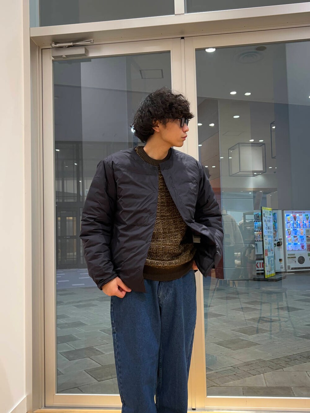 ブルー系のデニムパンツ、ブラック系のダウンジャケット/コート、ブラウン系のニット/セーターを着用したメンズの冬コーディネートの3枚目の写真