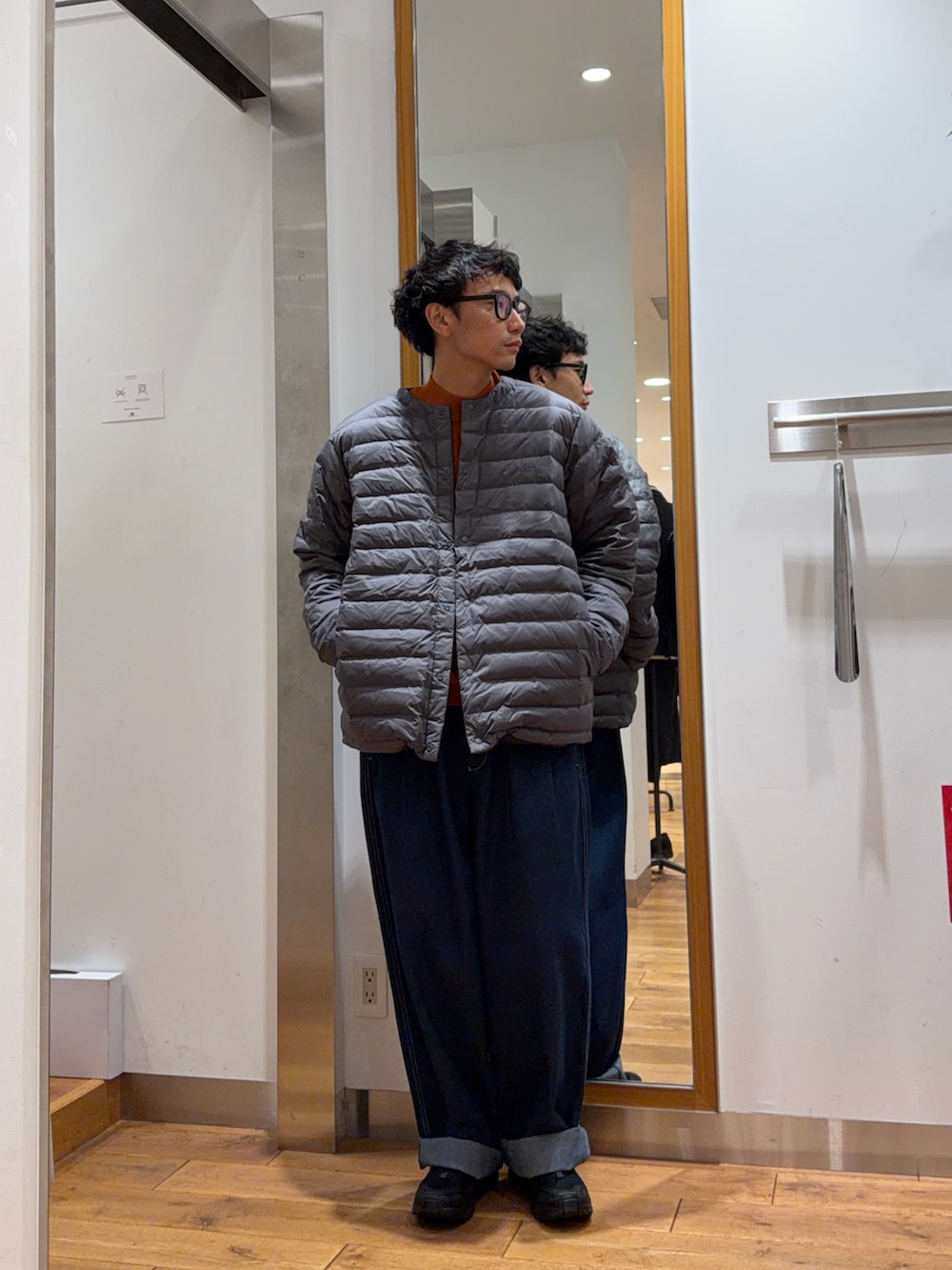 ブルー系のその他パンツ、オレンジ系のニット/セーター、ブラック系のダウンジャケット/コートを着用したメンズの秋コーディネートの4枚目の写真