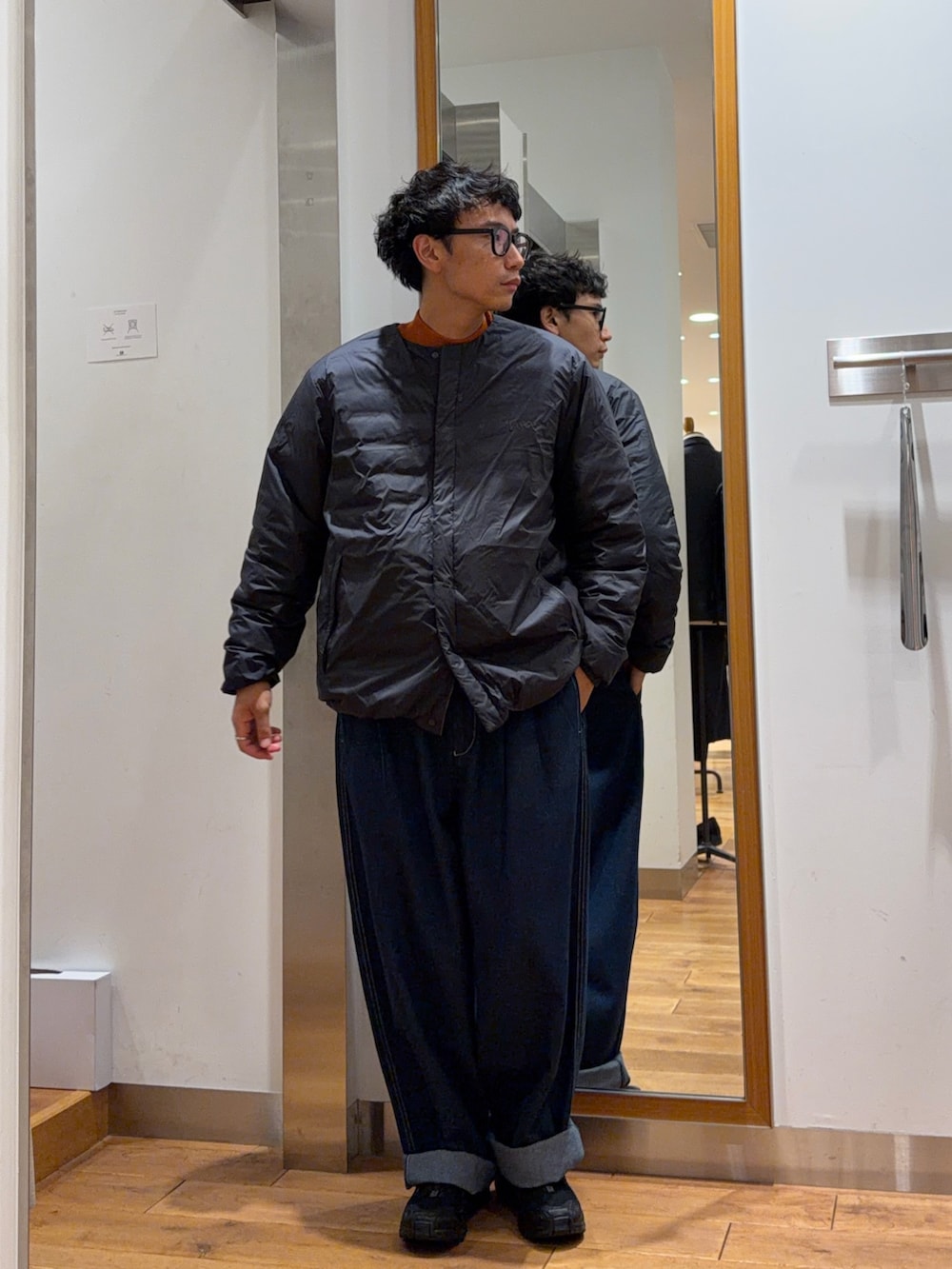 ブルー系のその他パンツ、オレンジ系のニット/セーター、ブラック系のダウンジャケット/コートを着用したメンズの秋コーディネートの2枚目の写真