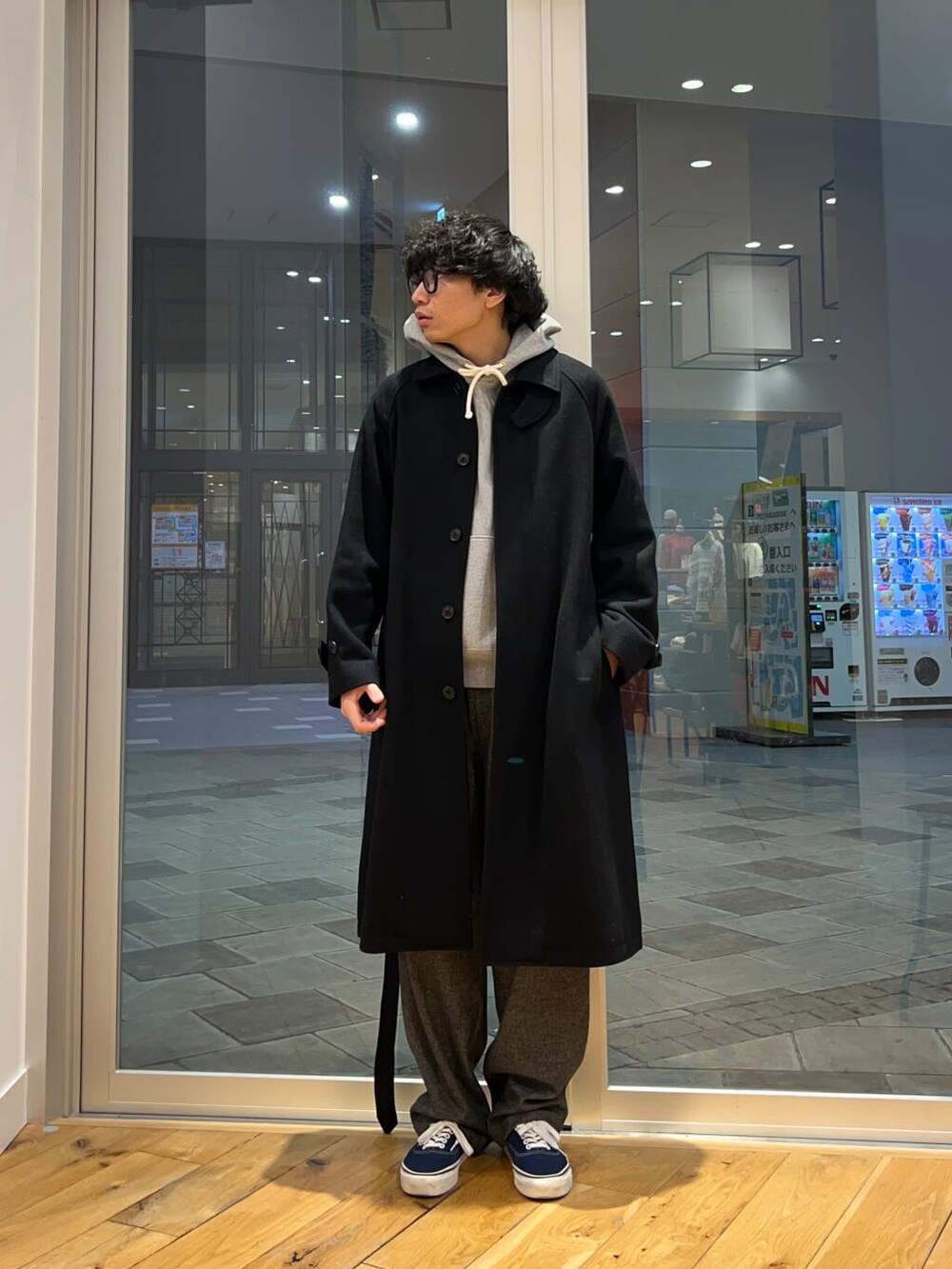 ブラック系のステンカラーコート、グレー系のその他パンツを着用したメンズの冬コーディネートの2枚目の写真