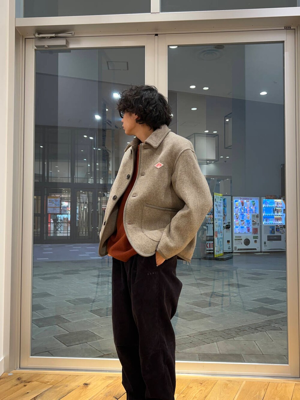 グレー系のその他パンツ、オレンジ系のニット/セーター、ベージュ系のカバーオールを着用したメンズの冬コーディネートの2枚目の写真